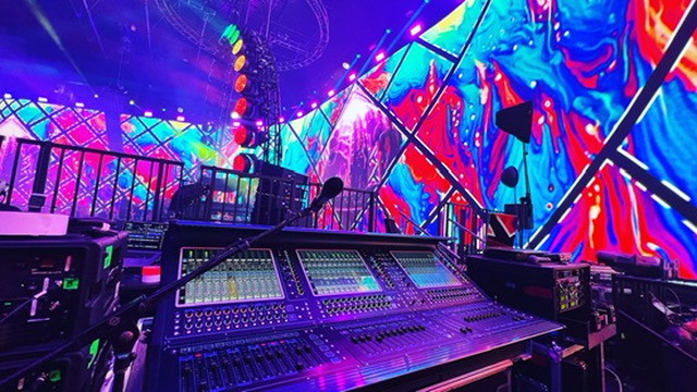Mixing console in front of a large colorful LED video wall
