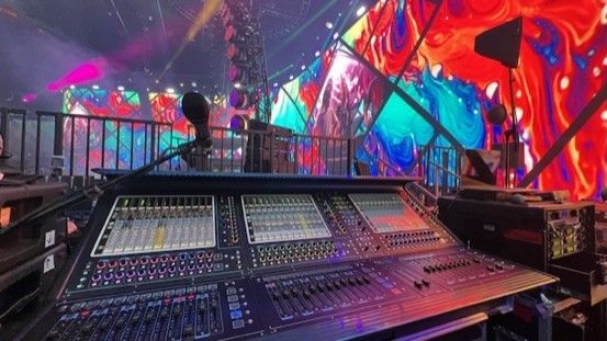 Wide view of a mixing console with a curved colorful video wall behind it