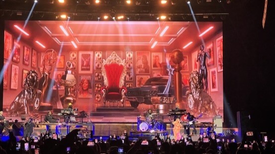 Wide stage with a red throne set on the video wall, seen from the audience