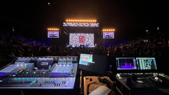 Console and screens at the mix position facing a lit arena stage