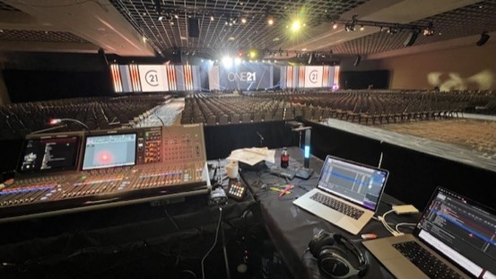Large ballroom set for a general session, with a console and two laptops at the mix position