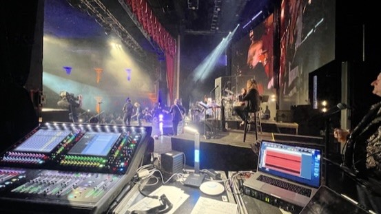 Console and a laptop running a recording session, facing a theater stage