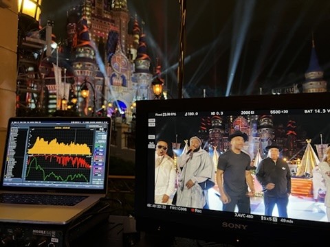 Close view of an audio analyzer and a video monitor showing a group of performers