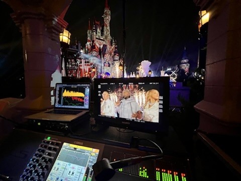 Laptop and video monitor on a balcony overlooking a lit castle at night
