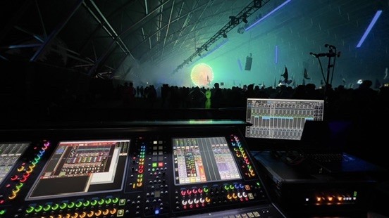 Digital console and a recording screen facing a dark stage with a glowing green moon