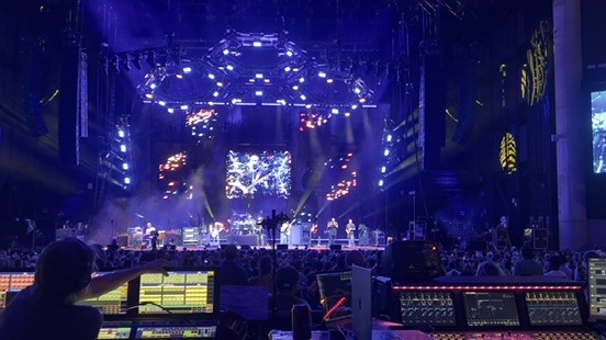 Arena stage and video screens seen from behind a console and monitor screens
