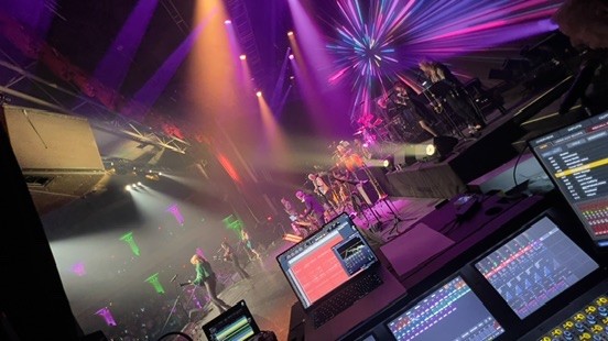 Band on stage with a starburst light effect, seen from behind the monitor position